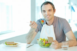 Ung mann spiser med serviett som beskytter klærne