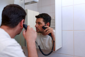 Mann som barberer seg foran speilet.